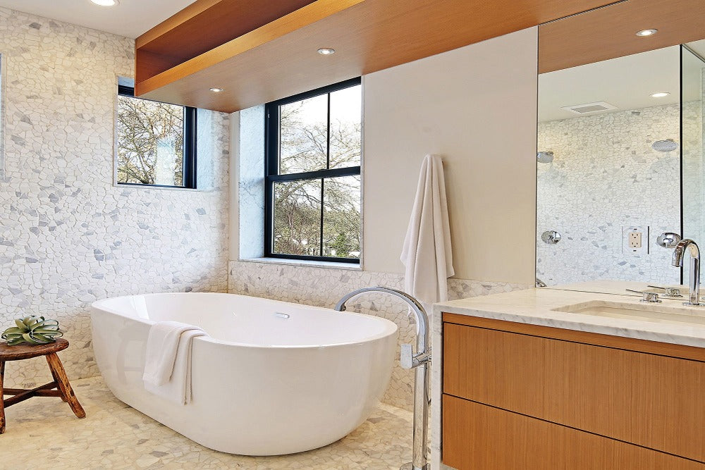 a free-standing bathtub in a modern well decorated bathroom with a White Colored Luxurious Bamboo Cotton Bath Towel draped over the bathtub and a White Colored Luxurious Bamboo Cotton Bath Sheet hanging on the wall behind the bathtub