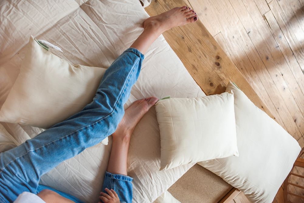 close up view of woman's legs and two wool filled pillows laying on the bed