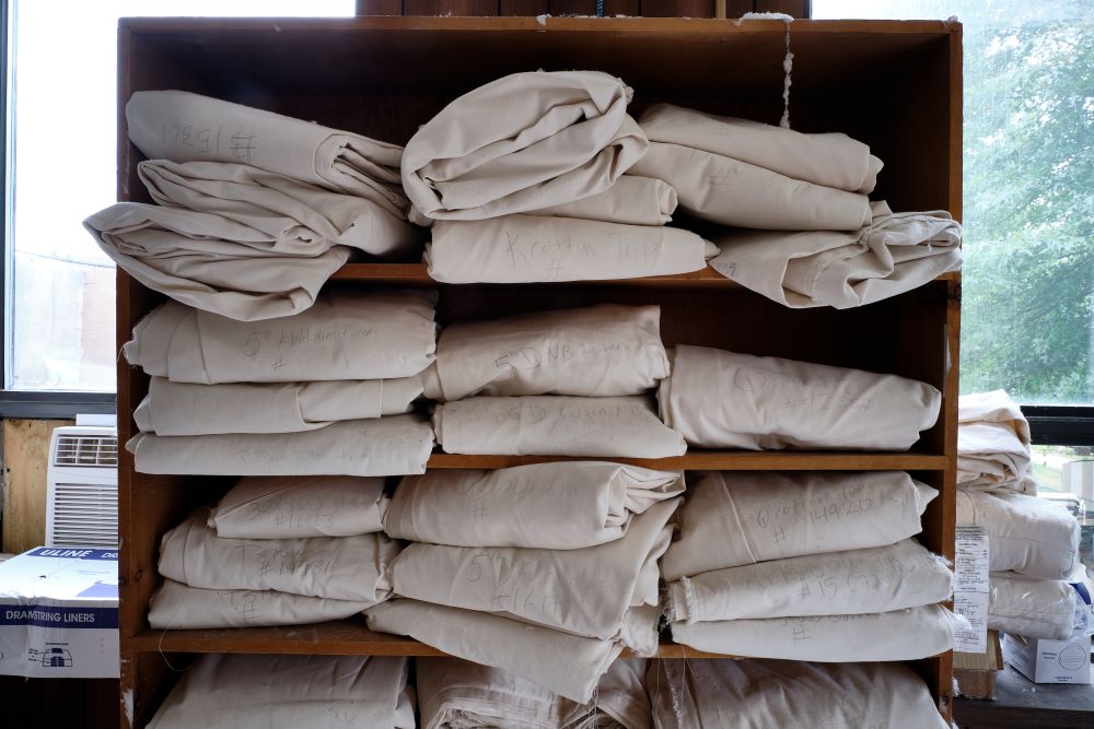 shelves filled with folded raw certified organic cotton material used to create soft luxurious sustainably sourced bedding